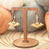 A pair of small bat-shaped dangling earrings.