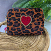 Leopard print handbag with a red heart and gold chain on a wooden surface.