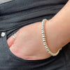 Close-up of a hand wearing a sterling silver beaded bracelet with a blurred background