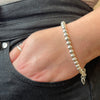 Hand wearing a sterling silver bead bracelet with a black background