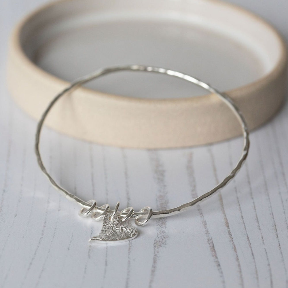 
                  
                    sterling silver textured tilted heart bangle handmade by lucy kemp jewellery
                  
                