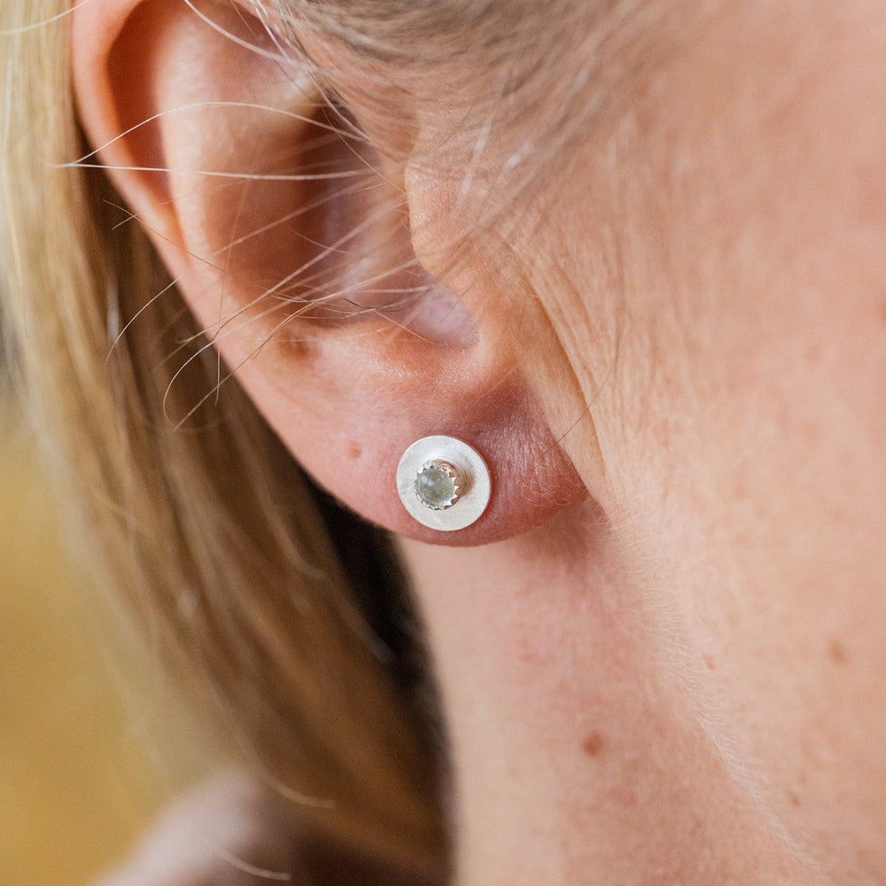 
                  
                    Worn Crystal Quartz and sterling silver birthstone small disc studs by Lucy Kemp Jewellery
                  
                