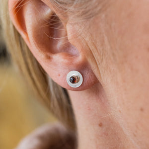 
                  
                    Worn Garnet and sterling silver birthstone small disc studs by Lucy Kemp Jewellery
                  
                