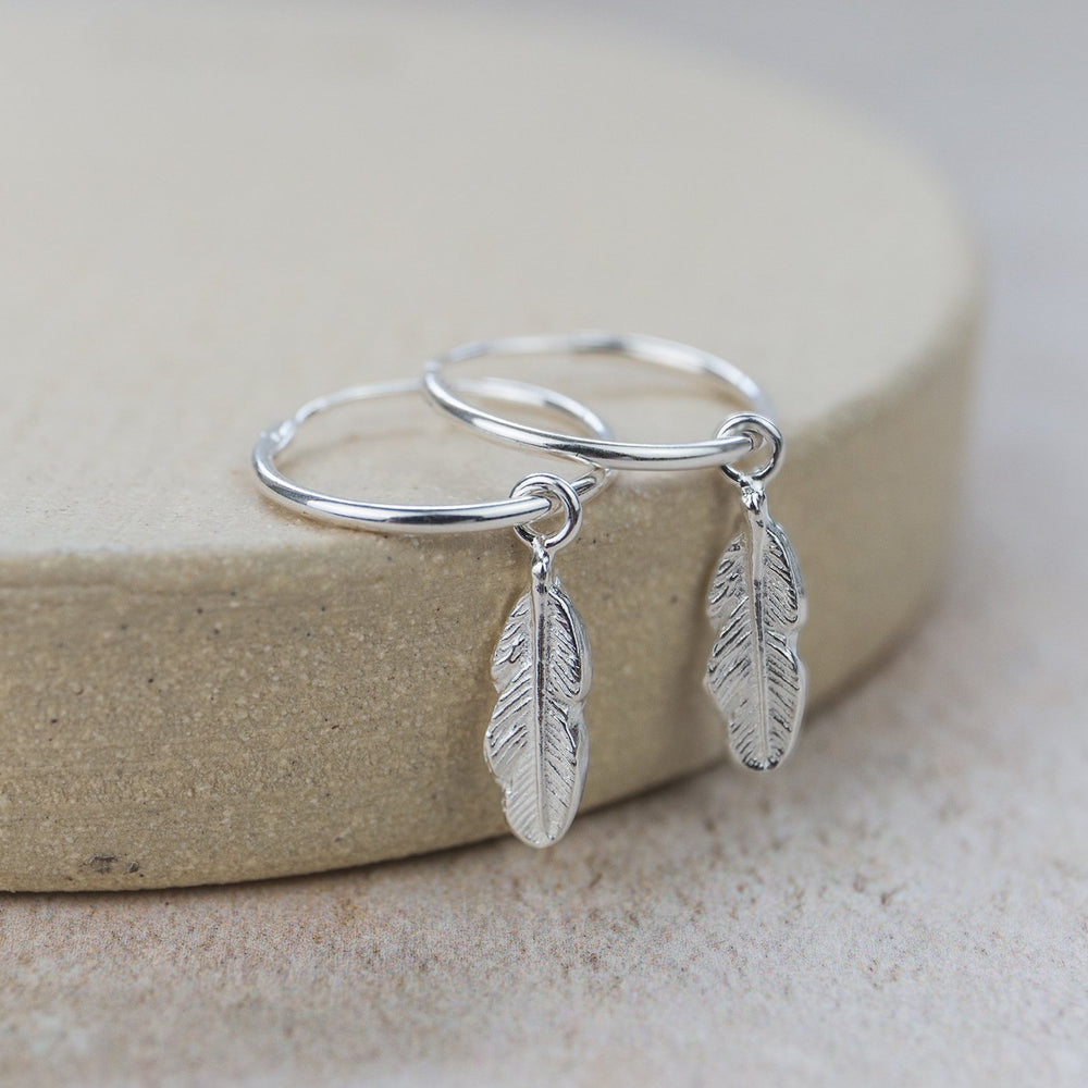 
                  
                    Sterling silver feather charm hoop handmade by Lucy Kemp Jewellery
                  
                