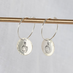 
                  
                    Sterling silver middle finger stamped charm hoops by Lucy Kemp Jewellery 
                  
                